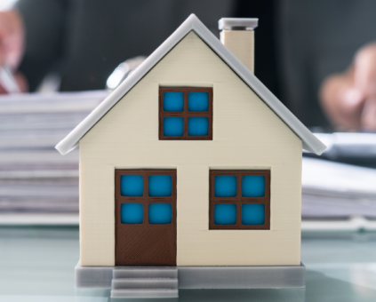 A small model house placed on an office desk whilst signing commercial property paperwork.